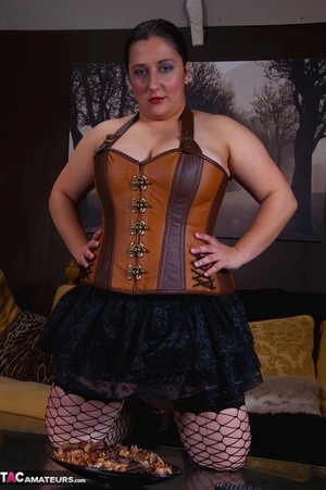 Gorgeous BBW pose her large body in different positions wearing her brown and orange corset, black skirt, panty, stockings and black and brown high heels on a black couch before she gets naked and expose her big tits while she screws her pussy with an orange dildo. - XXXonXXX - Pic 1