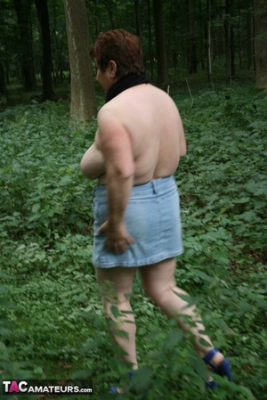 Chubby granny pose in the woods then peels off her black shirt and releases her giant tits before she pulls down her jeans skirt and teases with her humongous ass then pulls down her blue panty and expose her lusty pussy wearing her blue high heels. - XXXonXXX - Pic 4