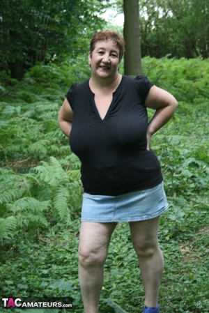 Mature BBW displays her plus size body in black shirt, jeans skirt and blue high heels then shows her extra large boobs in the woods. - Picture 2