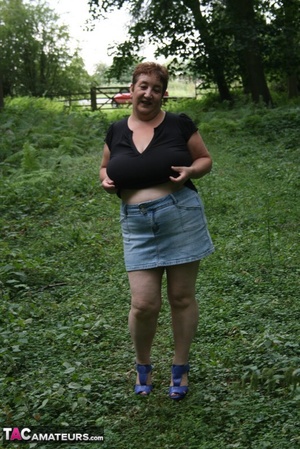 Mature BBW displays her plus size body in black shirt, jeans skirt and blue high heels then shows her extra large boobs in the woods. - Picture 18