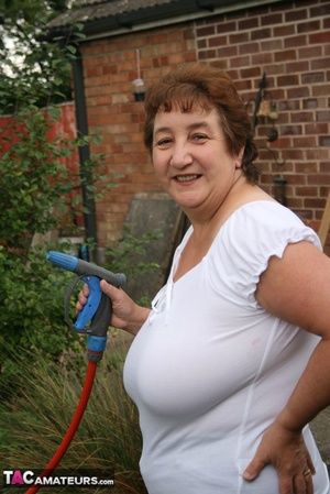 Plus size granny gets her big body wet with a hose on her lawn before she pulls down her jeans skirt and expose her lusty pussy then lifts up her white shirt and expose her humongous juggs. - XXXonXXX - Pic 1