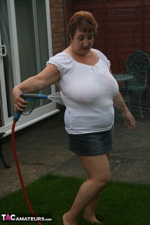 Plus size granny gets her big body wet with a hose on her lawn before she pulls down her jeans skirt and expose her lusty pussy then lifts up her white shirt and expose her humongous juggs. - Picture 4