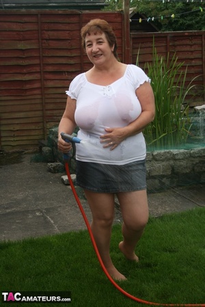 Plus size granny gets her big body wet with a hose on her lawn before she pulls down her jeans skirt and expose her lusty pussy then lifts up her white shirt and expose her humongous juggs. - Picture 8