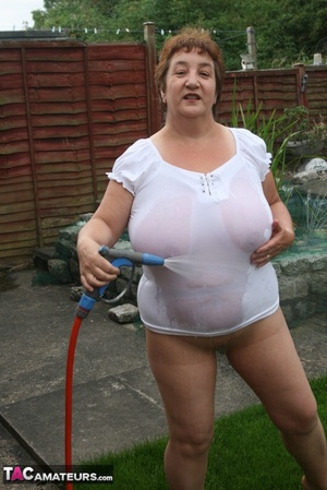 Plus size granny gets her big body wet with a hose on her lawn before she pulls down her jeans skirt and expose her lusty pussy then lifts up her white shirt and expose her humongous juggs. - Picture 12