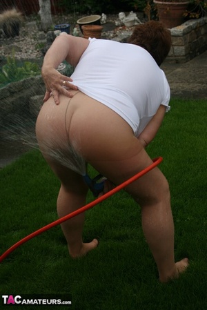 Plus size granny gets her big body wet with a hose on her lawn before she pulls down her jeans skirt and expose her lusty pussy then lifts up her white shirt and expose her humongous juggs. - Picture 14