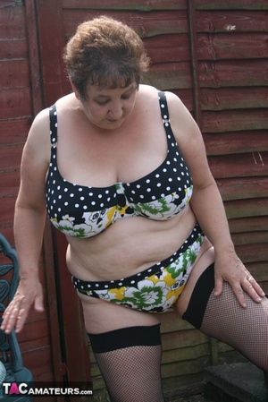 Steaming hot granny peels off her black blouse and yellow skirt and displays her chubby body in multi, colored underwear, black stockings and yellow high heels outdoor. - XXXonXXX - Pic 19