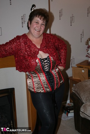 Chubby granny takes off her red blouse and displays her big body before she takes off her multi colored leopard print corset and expose her large breasts in different poses wearing her black leggings and brown and black high heels on the floor. - Picture 4