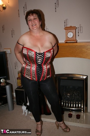 Chubby granny takes off her red blouse and displays her big body before she takes off her multi colored leopard print corset and expose her large breasts in different poses wearing her black leggings and brown and black high heels on the floor. - Picture 11