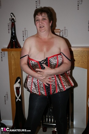 Chubby granny takes off her red blouse and displays her big body before she takes off her multi colored leopard print corset and expose her large breasts in different poses wearing her black leggings and brown and black high heels on the floor. - Picture 12
