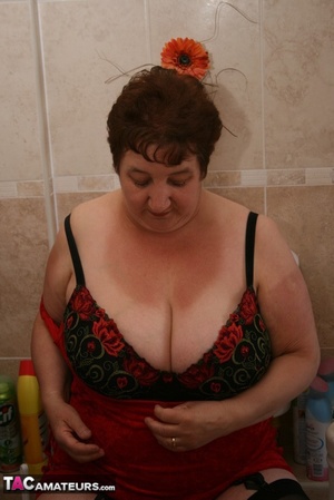 Alluring granny peels off her red dress and seduces with her plus size body in red and black lingerie, black stockings and red high heels in different poses in the bathroom. - XXXonXXX - Pic 15