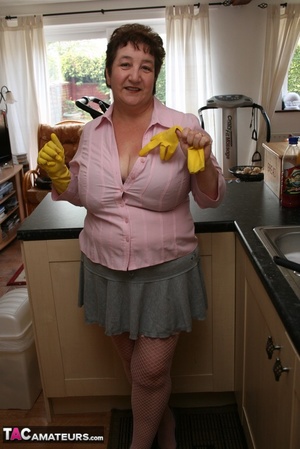 Mature plomper displays her chubby body in pink shirt, gray skirt, underwear, pink stockings and gray high heels in different poses in her kitchen. - Picture 6