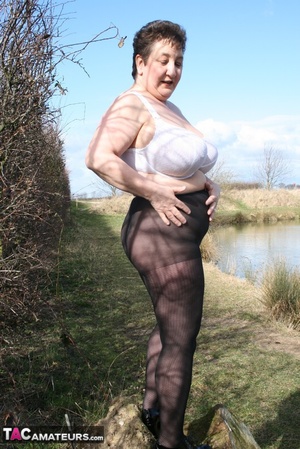 Mature BBW shows her gigantic breasts as she pose in a forest wearing her white bra, black and white skirt, black stockings and high heels before she gets naked and shows her juicy pussy in different positions. - Picture 6