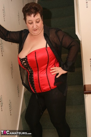Cute granny peels off her black see through blouse and teases with her plus size body in different poses on a green stairway wearing her red and black corset, black leggings and high heels. - XXXonXXX - Pic 11