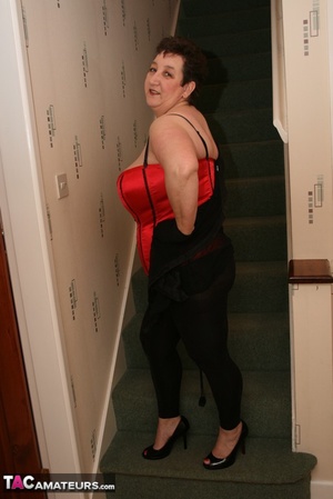 Cute granny peels off her black see through blouse and teases with her plus size body in different poses on a green stairway wearing her red and black corset, black leggings and high heels. - XXXonXXX - Pic 13
