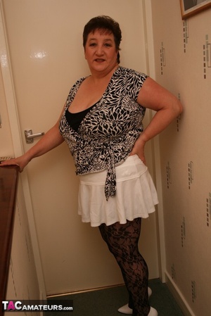 Mature chick teases with her chubby body black and white blouse, white skirt, black bra, white panty, black stockings and white high heels before she gets naked and bares her monster tits and indulging pussy in different poses on a gray stairway. - XXXonXXX - Pic 2