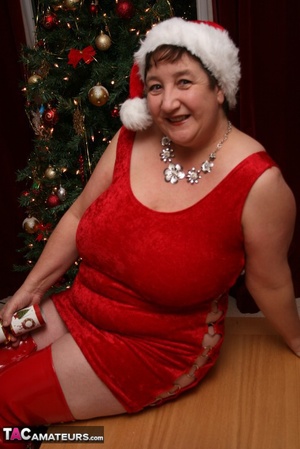 Mature plomper displays her large body in red santa hat, dress, panty and boots on a gray and brown couch before she reveals her monster boobs and juicy pussy in different poses. - XXXonXXX - Pic 1