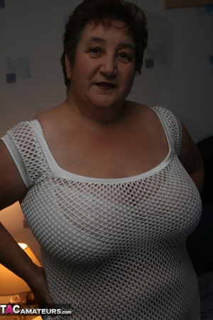 Naughty granny displays her plus size body before she expose her humongous tits in different poses wearing her white dress, lingerie and boots on a blue bed. - Picture 2