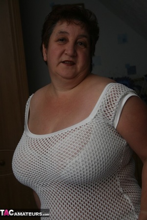 Naughty granny displays her plus size body before she expose her humongous tits in different poses wearing her white dress, lingerie and boots on a blue bed. - Picture 11
