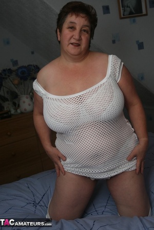 Naughty granny displays her plus size body before she expose her humongous tits in different poses wearing her white dress, lingerie and boots on a blue bed. - Picture 12