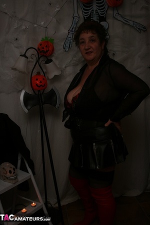 Hot granny takes off her black jacket and teases with her monster tits and chubby body in red and black lingerie, black skirt, stockings and red boots. - Picture 2