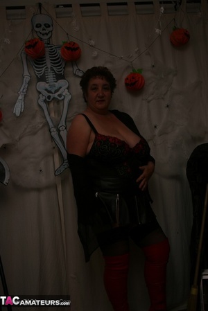 Hot granny takes off her black jacket and teases with her monster tits and chubby body in red and black lingerie, black skirt, stockings and red boots. - Picture 10