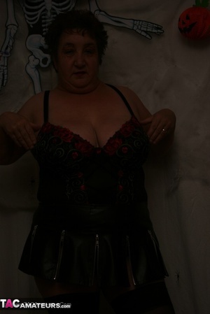 Hot granny takes off her black jacket and teases with her monster tits and chubby body in red and black lingerie, black skirt, stockings and red boots. - Picture 16
