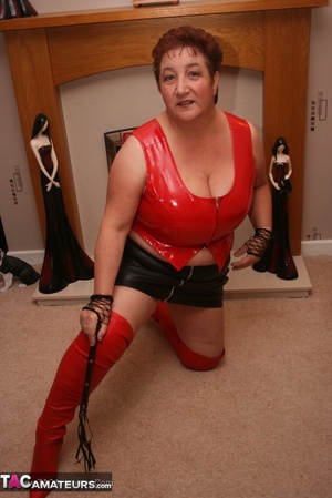 Luscious granny pose her plus size body in red leather shirt, black skirt, red panty and leather boots in different poses before she bends over and whips her twat. - Picture 10