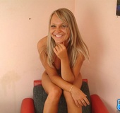 Busty blonde in jeans miniskirt and pink undies strips on the red chair