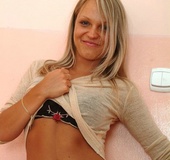 Busty blonde in black heels and underwear getting nude by the wall and