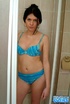 Dark haired beauty in blue bikini taking a shower before undressing and