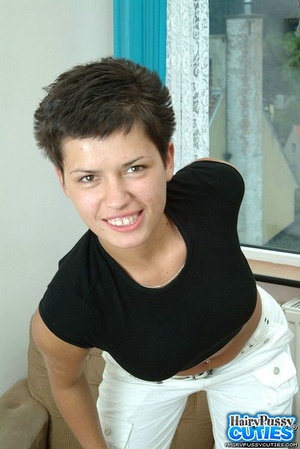 Short haired brunette in black t-shirt and white panty strips on the chair and shows her hairy vagina - Picture 1