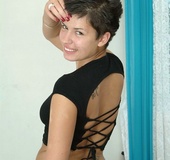 Busty brunette with pierced belly and red nails sheds black top and white