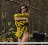 Short haired brunette in long green dress stripteasing in the forest and
