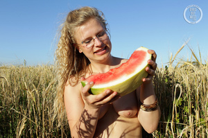 Blonde babe with glasses teases with her foxy body while she eats her watermelon in a crop field before she stips off her white dress and shows her lusty pussy and sweet crack in different poses in a crop field. - Picture 5