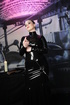 Brunette in black latex is in a colorful room playing with bdsm toys
