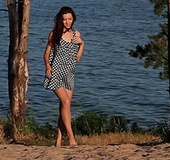 Long haired brunette in short dress teasing outdoors on the beach and