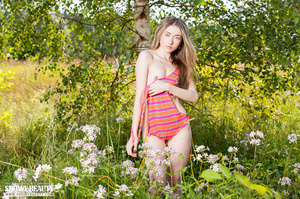 Alluring babe in orange and pink leotard and orange skirt displays her indulging body in a flower field before she gets naked and bares her tiny tits and lusty pussy in different poses. - Picture 11