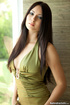 Green dress blue-eyed brunette gets naked next to a glass door
