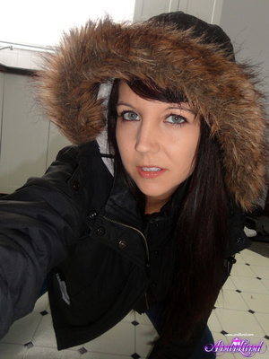 Winter jacked brunette takes off her clothes on the floor - Picture 1