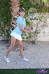 Young brunette tennis player wearing blue top with flowy white skirt pulls