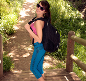 Tattooed brunette with belly ring wearing pink sports bra and blue leggings