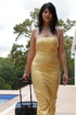 Yellow latex dress brunette posing next to a swimming pool with suitcase