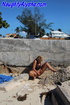Blonde milf exhhibitionist sits by concrete wall during a warm day wearing