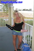 Tanned blonde wearing black and neon green tank top with denim heels and