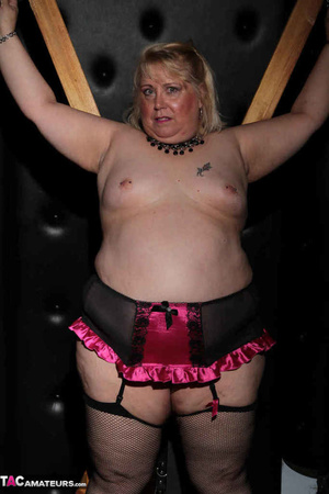 Blonde bbw with pierced nipples posing in fishnet hose and showing her pink snatch in the bdsm dungeon - Picture 2
