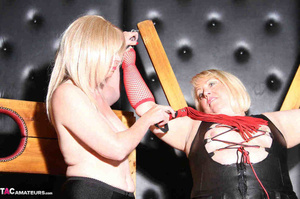 Two blonde milfs in stockings and leather outfit undressing one other before posing in the bdsm dungeon - Picture 15