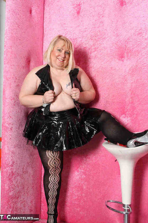 Big blonde in black leather outfit and black stockings stripteasing by the pink wall and showing her pierced vagina - XXXonXXX - Pic 9