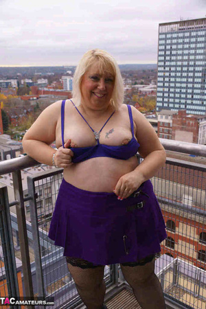 High heeled bbw in black stockings and purple miniskirt sheds blue bra and exposing her pierced snatch on the balcony - Picture 11