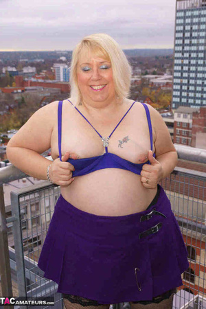 High heeled bbw in black stockings and purple miniskirt sheds blue bra and exposing her pierced snatch on the balcony - Picture 12
