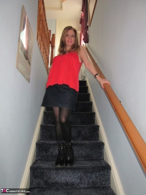 Mature chick in black stockings taking off red top and lacy panty on the stairs just to show her naked goods - Picture 1